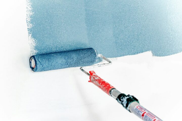 Paint roller on an extension pole applying a coat to a wall, showing the roller technique used when applying epoxy paint