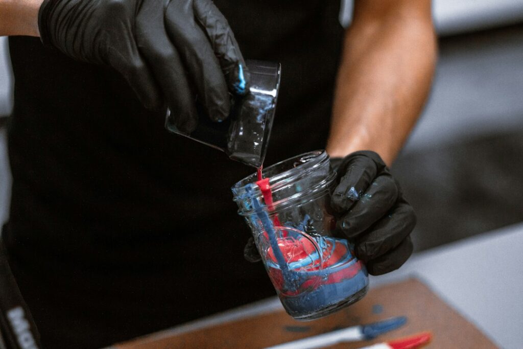 Hand holding a clear cup of liquid, illustrating measuring and mixing clear epoxy resin