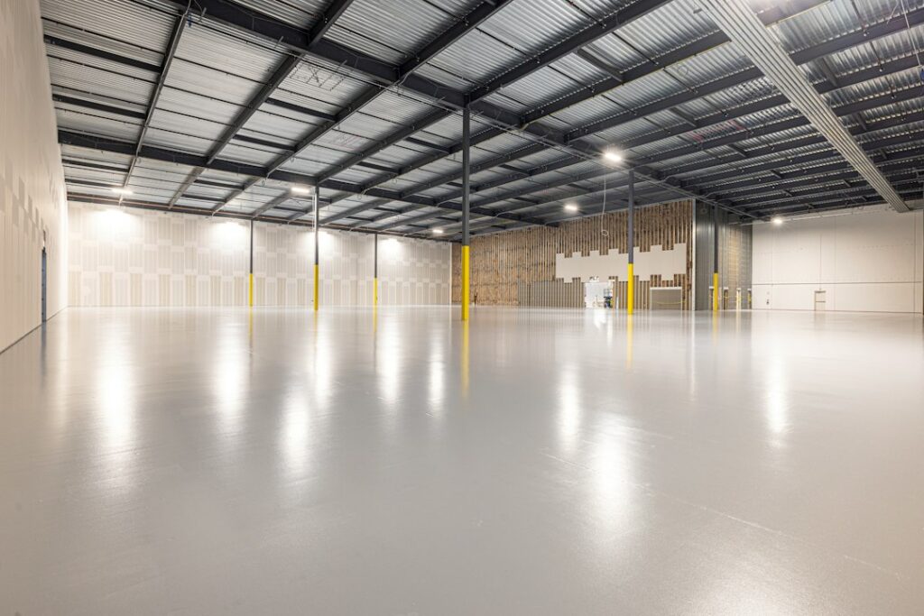 Large industrial facility with a seamless glossy industrial epoxy flooring system, compared with residential garage coatings