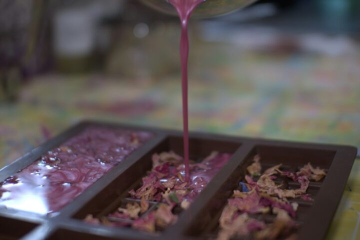 Pink coloured epoxy being poured into a tray, one of many resin molds used for casting